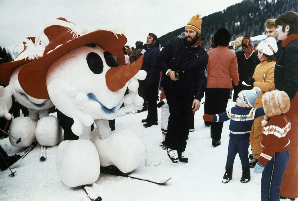 A snowman, mascot of the 1976 Winter Olympics in Innsbruck, greets children in Kitzbuhel, Austria, during the world downhill ski events, January 1975. (AP Photo)