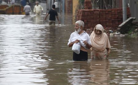 A couple wades through a flooded road after heavy rains in Lahore September 4, 2014. REUTERS/Mohsin Raza