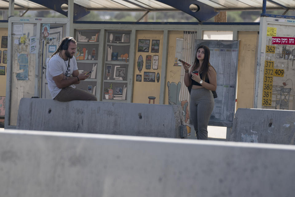 Israeli settlers wait a bus stop at the Gush Etzion junction, the transportation hub for a number of West Bank Jewish settlements, Thursday, June 9, 2022. Israeli settlers in the occupied West Bank may soon have a taste of the military rule that Palestinians have been living under for 55 years. A looming end-of-month deadline to extend legal protections to Jewish settlers has put Israel’s government on the brink of collapse and drawn widespread warnings that the territory could be plunged into chaos. (AP Photo/Maya Alleruzzo)