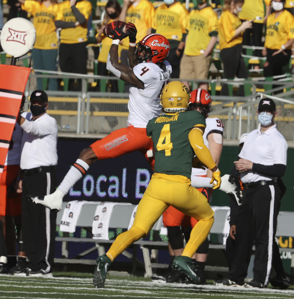 Oklahoma State wide receiver Tay Martin, left, pulls down a pass over Baylor safety Christian Morgan, right, in the first half of an NCAA college football game, Saturday, Dec. 12, 2020, in Waco, Texas. (Rod Aydelotte/Waco Tribune-Herald via AP)