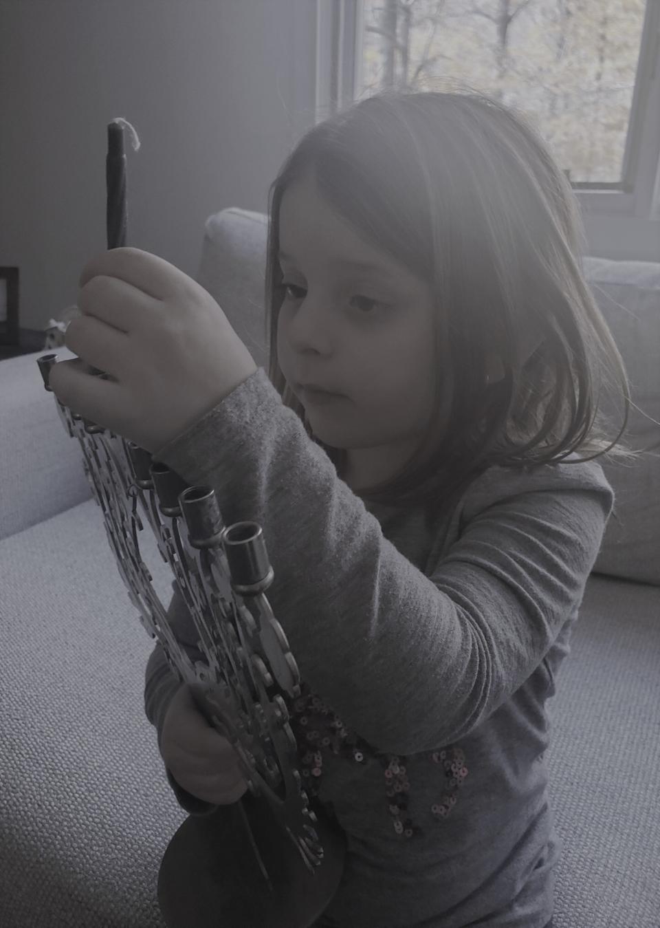 Fiona Cohen, 5, of Doylestown, carefully handles a menorah as her family prepares for the start of Hanukkah, which runs from Sunday evening until the evening of Dec. 6.