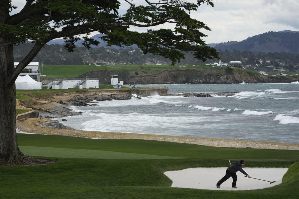 A caddie rakes a bunker near the 18th green of the Pebble Beach Golf Links during a practice round of the AT&T Pebble Beach National Pro-Am golf tournament in Pebble Beach, Calif., Wednesday, Jan. 31, 2024. (AP Photo/Eric Risberg)