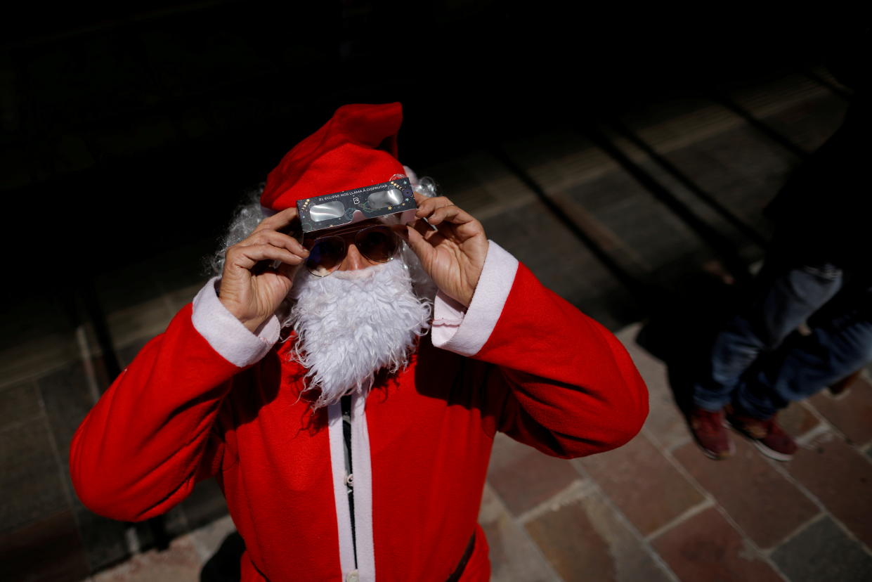 2020: A man dressed as Santa Claus uses special protective glasses to observe the solar eclipse in Bariloche, Patagonia, Argentina. 