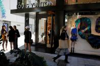 People walk past the Louis Vuitton store at Miami Design District, in Miami