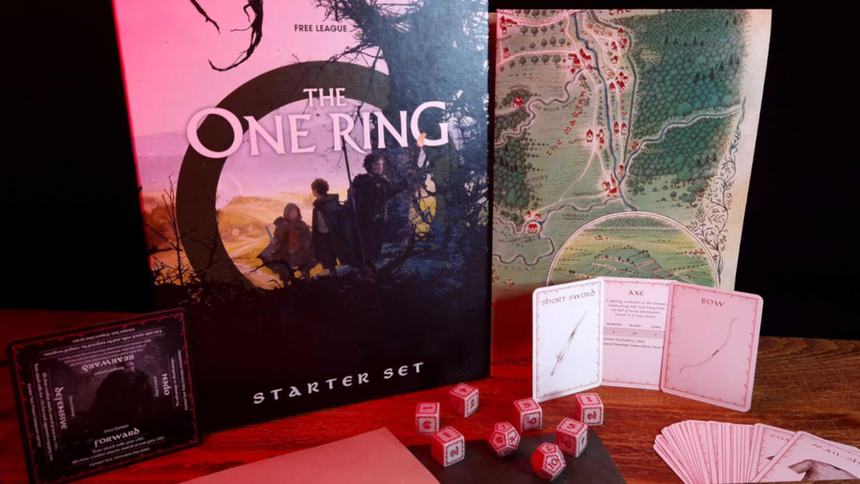  The One Ring Starter Set box, map, cards, and dice on a wooden table against a dark backdrop 