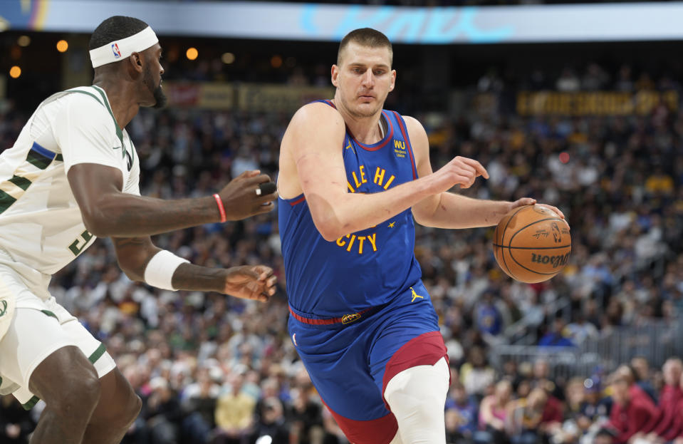 Denver Nuggets center Nikola Jokic, right, drives the lane as Milwaukee Bucks forward Bobby Portis defends in the first half of an NBA basketball game Saturday, March 25, 2023, in Denver. (AP Photo/David Zalubowski)