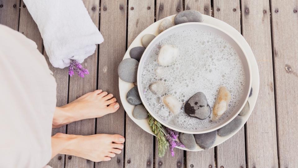 A woman standing in front of a bowl filled with water and rocks for a soak