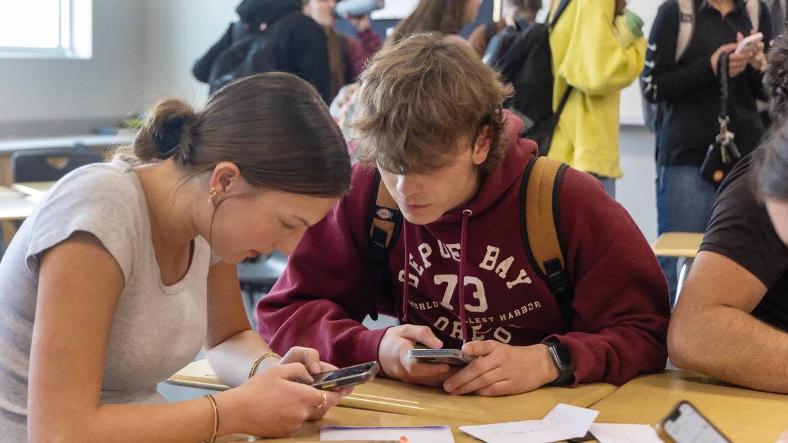 Owyhee High School juniors Avery Endow, 17, and Hunter Williams, 17, look at maps on their phones at the end of the class period after they are allowed to retrieve their phones from the VAULT.