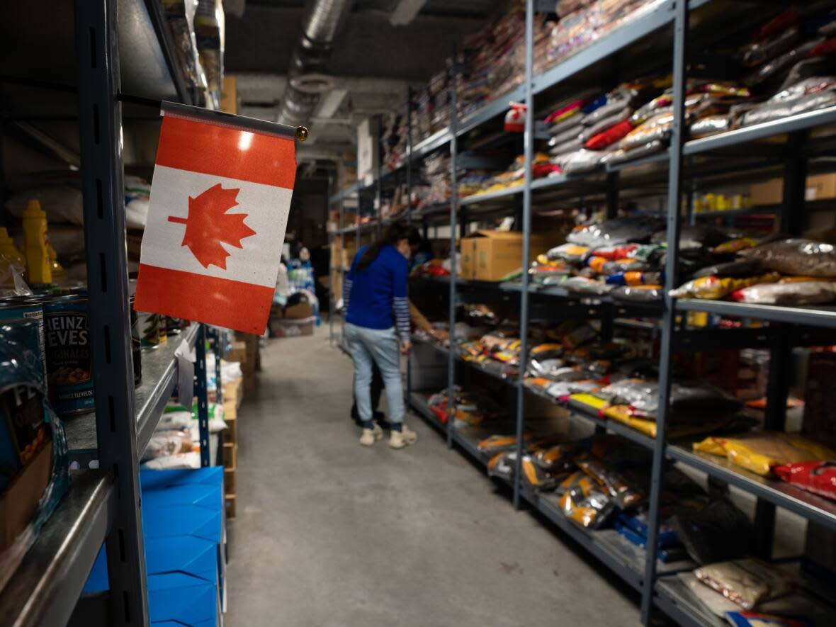 Volunteers select food items from shelves at Guru Nanak Food Bank in Surrey, B.C. Food prices are the highest they've been in Canada for decades, according to Statistics Canada.  (Maggie MacPherson/CBC - image credit)