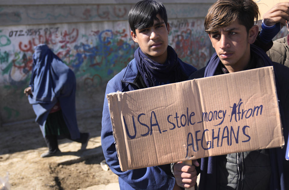 Afghan protesters hold placards and shout slogans against U.S. during a protest condemning President Joe Biden's decision, in Kabul, Afghanistan, Saturday, Feb. 12, 2022. President Biden signed an executive order, Friday, Feb. 11, 2022, to create a pathway to split $7 billion in Afghan assets frozen in the U.S. to fund humanitarian relief in Afghanistan and to create a trust fund to compensate Sept. 11 victims. (AP Photo/Hussein Malla)