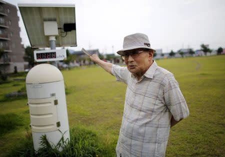 Atsushi Hoshino, a 87-year-old Hiroshima atomic bombing survivor, former college professor and ex-president of Fukushima University, speaks next to a radiation monitoring post measuring a radiation level of 0.123 microsievert per hour, at a park near his home in Fukushima, Japan, July 30, 2015. REUTERS/Toru Hanai