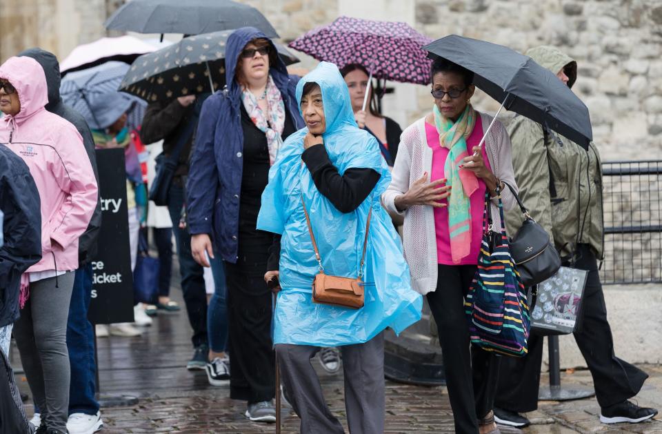 Tourists caught in heavy rain showers at the Tower of London (Rex)