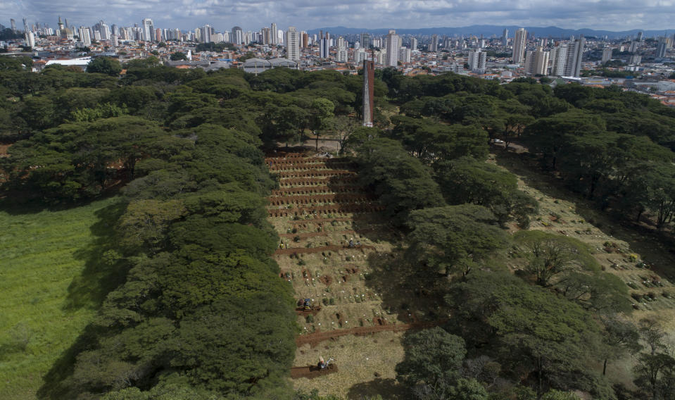 Workers use small bulldozers to dig more graves amid the COVID-19 pandemic at the Vila Formosa cemetery in Sao Paulo, Brazil, Wednesday, April 7, 2021. The city of Sao Paulo started on Wednesday the digging of 600 additional graves every day in its municipal cemeteries. (AP Photo/Andre Penner)