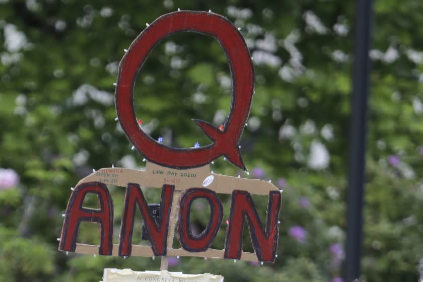 FILE - In this May 14, 2020, file photo, a person carries a sign supporting QAnon during a protest rally in Olympia, Wash, USA. The social media company Twitter said Tuesday Jan. 12, 2021, it has suspended more than 70,000 accounts associated with the far right QAnon conspiracy theory following last week's U.S. Capitol insurrection. (AP Photo/Ted S. Warren, File)