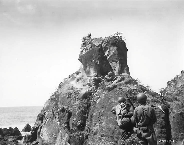 U.S. forces fire a Bazooka rocket into the mouth of a cave along Iwo Jima's rugged northern coast