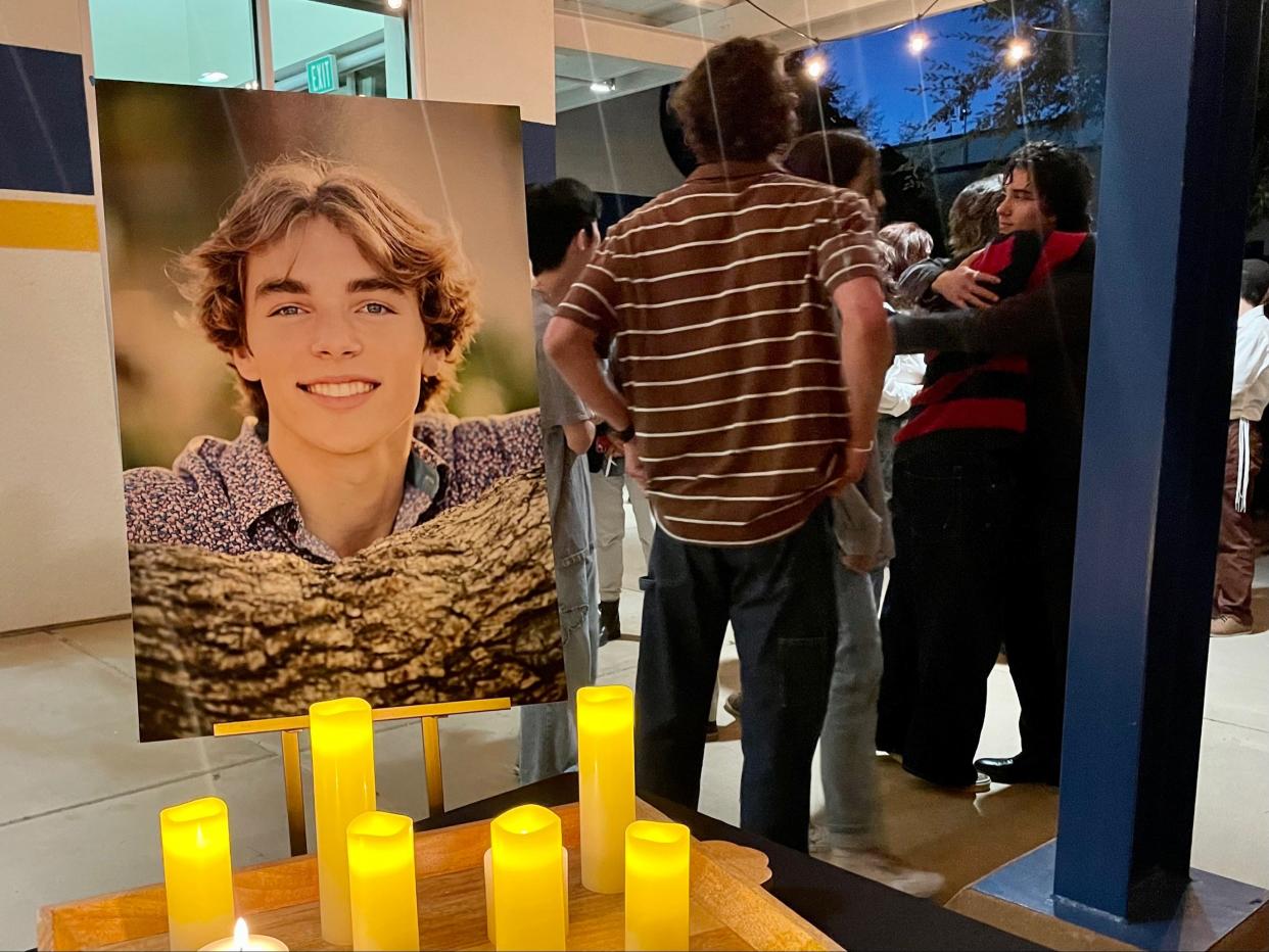 Mourners hug near a photo of Benny Schurmer during a candlelight vigil for the Nordhoff High School alum at the Ojai school Thursday night.