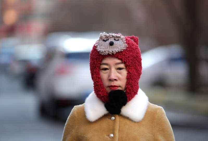 A woman walks at a residential area on a cold winter day in Harbin