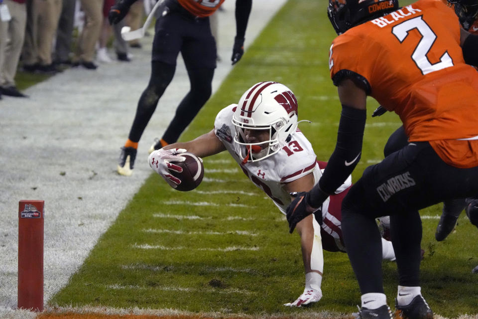 Wisconsin wide receiver Chimere Dike dives for the end zone in front of Oklahoma State cornerback Korie Black (2) during the first half of the Guaranteed Rate Bowl NCAA college football game Tuesday, Dec. 27, 2022, in Phoenix. (AP Photo/Rick Scuteri)