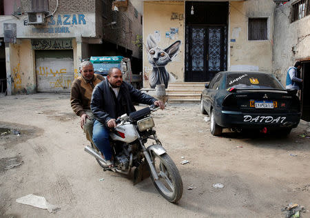 People ride a motorcycle in front of a graffiti painted on the wall of a house located inside the 15th-century complex built by Mameluk Sultan al-Ashraf Qaitbey, in Cairo's City of the Dead, Egypt February 13, 2017. REUTERS/Amr Abdallah Dalsh