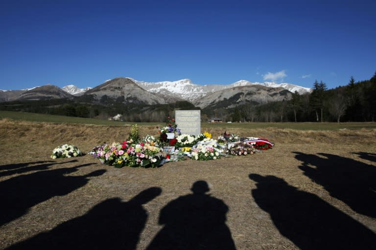 This file photo taken on April 6, 2015 shows people's shadows as they stand near a stela commemorating the victims of the March 24 Germanwings Airbus A320 crash in the village of Le Vernet, southeastern France, after a ceremony with victims' relatives