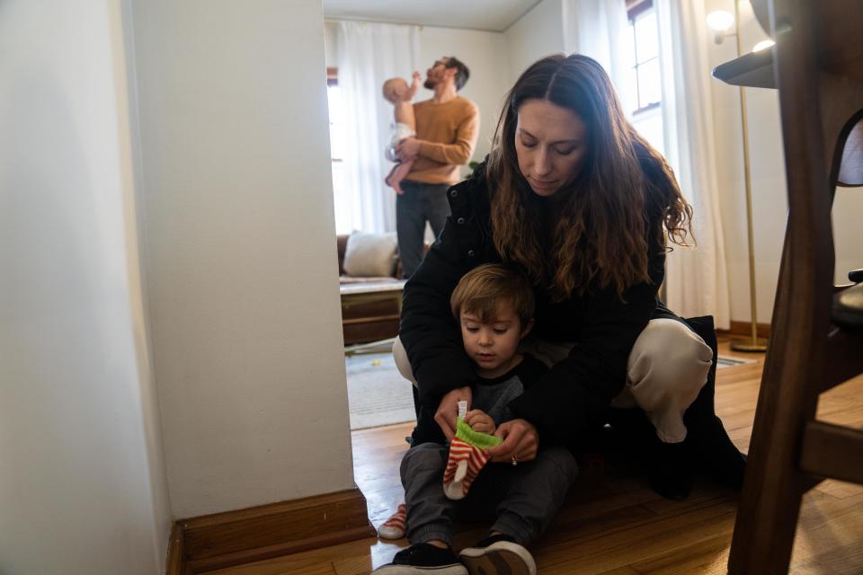 Emily Donlin puts mittens on her son Walter as her husband, Michael, holds their 9-month-old son, Paul, Tuesday, Dec. 5, 2023, in Des Moines. After Paul's birth, the umbilical cord was screened in a nonconsensual drug test, which came back positive for cocaine. The family claims the test results were a false positive.