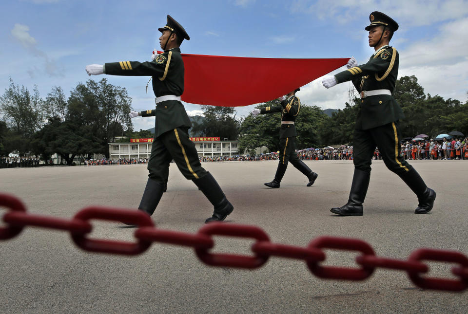 FILE - In this June 29, 2014, file photo, soldiers carry a Chinese national flag at a military base during an open day event of the Chinese People's Liberation Army (PLA) in Hong Kong. A year after Beijing imposed a harsh national security law on Hong Kong, the civil liberties that raised hopes for more democracy are fading.(AP Photo/Vincent Yu, File)