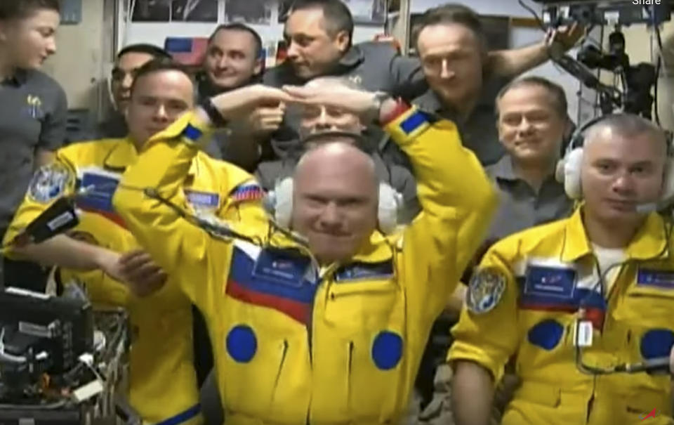 In this photo taken from video footage released by the Roscosmos Space Agency, newly arrived to the ISS, wearing yellow suits, Russian cosmonauts Оleg Аrtemiev, center, Denis Мatveev, right, and Sergei Korsakov pose among other participants of expedition to the International Space Station, ISS, after docking the Soyuz MS-21 spaceship to the station, Friday, March 18, 2022. (Roscosmos Space Agency via AP)