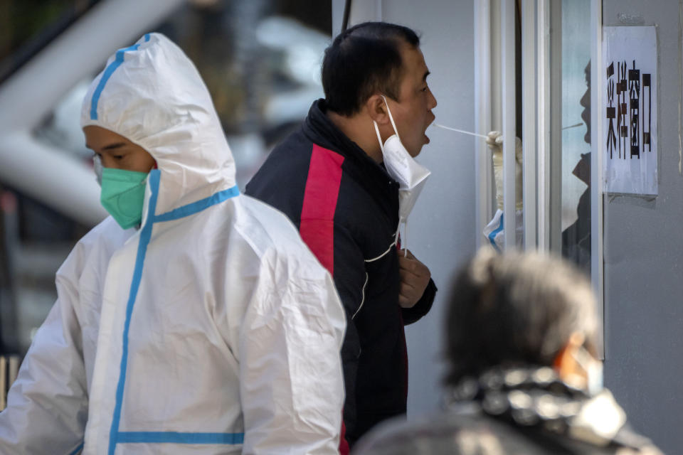 A man has his throat swabbed for a COVID-19 test at a coronavirus testing site in Beijing, Tuesday, Nov. 1, 2022. Shanghai Disneyland was closed and visitors temporarily kept in the park for virus testing, the city government announced, while social media posts said some amusements kept operating for guests who were blocked from leaving. (AP Photo/Mark Schiefelbein)