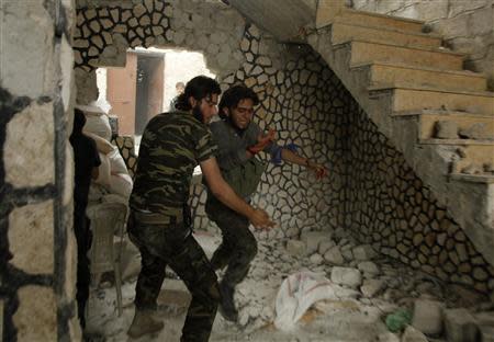 A Free Syrian Army fighter helps his wounded fellow fighter in Al-Amariya district in Aleppo May 8, 2014. REUTERS/Ammar Abdullah