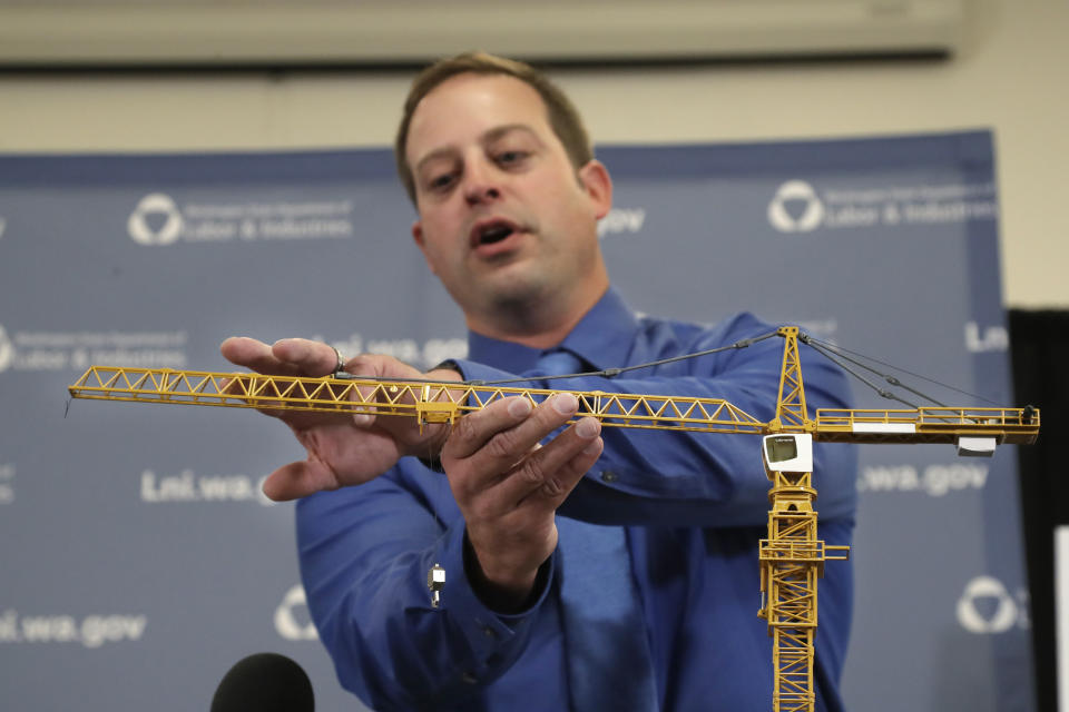 Brian Haight, crane program manager for Washington state's Department of Labor and Industries, uses a model of a crane during a news conference to explain the collapse of a crane earlier in the year in Seattle that killed four, Thursday, Oct. 17, 2019, in Tukwila, Wash. Washington state's L&I released the results of its investigation on the collapse Thursday. It found, as experts have long suspected, that the crane toppled because workers who were disassembling it had prematurely removed pins securing the sections of the crane's mast. (AP Photo/Elaine Thompson)