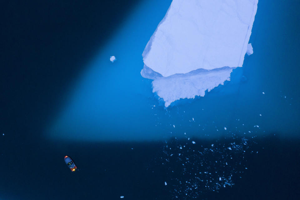 In this Aug. 15, 2019, photo, a boat navigates next to a large iceberg in eastern Greenland. Greenland's ice has been melting for more than 20 years, but in 2019, it's as if Earth's refrigerator door has been left open, and it means a potentially large rise in the world's sea levels. (AP Photo/Felipe Dana)