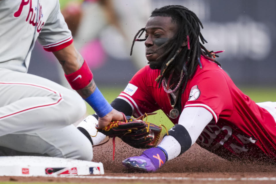 Cincinnati Reds' Elly De La Cruz, right, slides into third base on an error by Philadelphia Phillies third baseman Edmundo Sosa during the third inning of a baseball game in Cincinnati on Friday, Wednesday, April 24, 2024. (AP Photo/Aaron Doster)