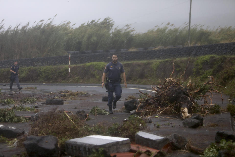 Portuguese coastguard officers walk among debris blocking a road in the seafront village of Feteira, outside Horta, in the Portuguese island of Faial, Wednesday, Oct. 2, 2019. Hurricane Lorenzo is lashing the mid-Atlantic Azores Islands with heavy rain, powerful winds and high waves. The Category 2 hurricane passed the Portuguese island chain Wednesday. (AP Photo/Joao Henriques)