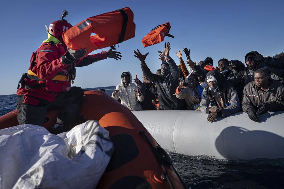 FILE - Migrants and refugees from Africa sailing adrift on an overcrowded rubber boat, receive life jackets from aid workers of the Spanish NGO Aita Mary in the Mediterranean Sea, about 103 miles (165 km) from Libya coast, Jan. 28, 2022. The back-to-back shipwrecks of migrant boats off Greece that left at least 22 people dead this week has once again put the spotlight on the dangers of the Mediterranean migration route to Europe. (AP Photo/Pau de la Calle, file)