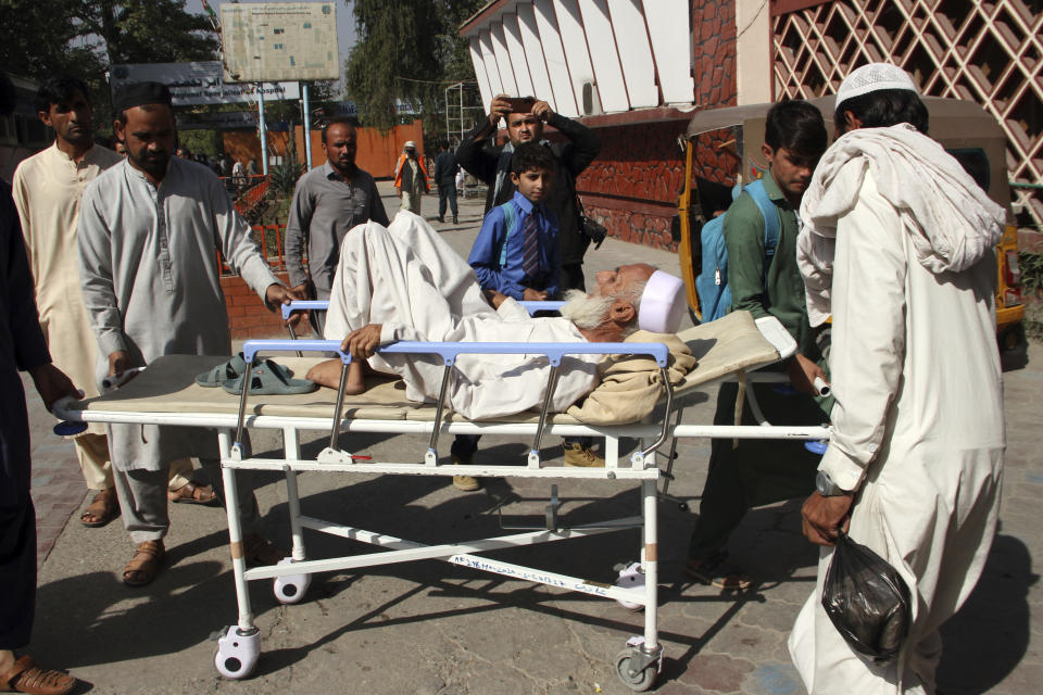 Afghan bring a man injured in a stampede to a hospital in the city of Jalalabad east of Kabul, Afghanistan, Wednesday, Oct. 21, 2020. At least 11 women were trampled to death when a stampede broke out Wednesday among thousands of Afghans waiting in a soccer stadium to get visas to Pakistan, officials said. (AP Photo/Wali Sabawoon)