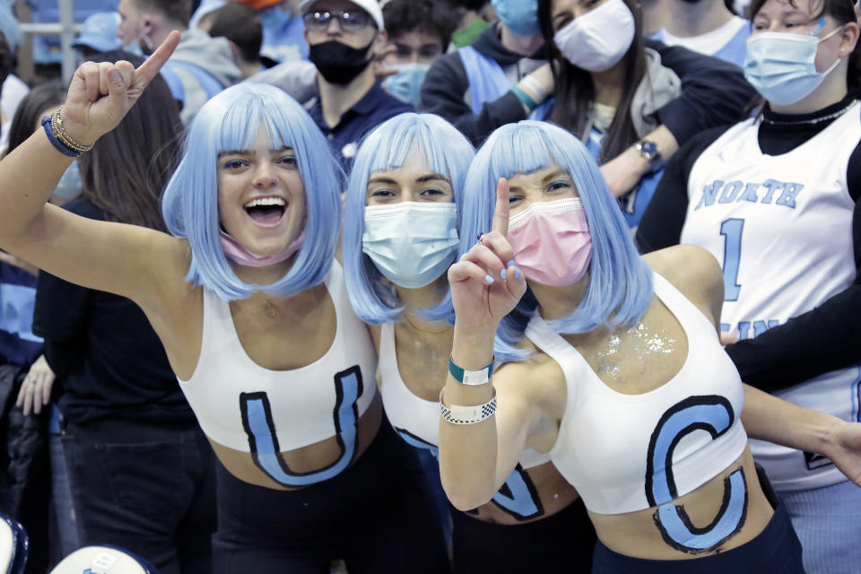 FILE - North Carolina fans don wigs in the team colors and cheer for the team before the start of of an NCAA college basketball game against Duke, Saturday, Feb. 5, 2022, in Chapel Hill, N.C. With four starters back from the team that blew a 15-point halftime lead to Kansas at the Superdome in New Orleans, the Tar Heels were the runaway pick as the preseason No. 1 in the AP Top 25 on Monday, Oct. 17, 2022.(AP Photo/Chris Seward, File)