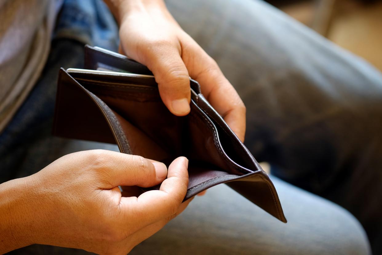 man looking at his empty leather wallet in office