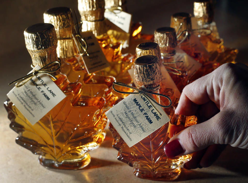 In this March 13, 2014 photo, Kathy Gallagher arranges bottles of maple syrup at the Turtle Lane Maple sugar house in North Andover, Mass. It takes about 40 gallons of sap to yield one gallon of syrup. Maple syrup season is finally under way in Massachusetts after getting off to a slow start because of unusually cold weather. (AP Photo/Elise Amendola)