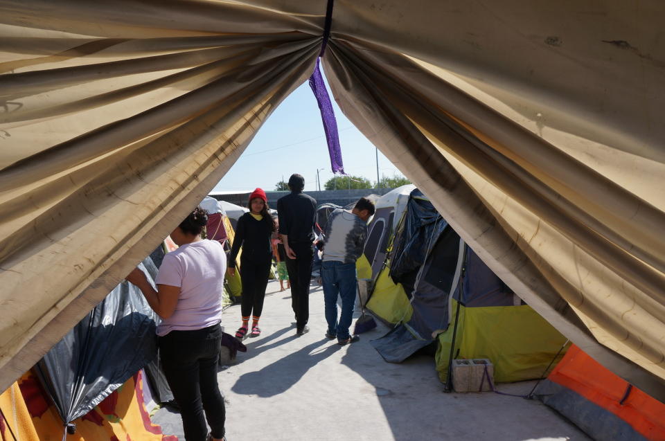 Migrants walk by their tents in the Senda de Vida 2 shelter in Reynosa, Mexico, Thursday, Dec. 15, 2022. Nearly three thousand people cram inside the vast compound of tents over cement or gravel by the Rio Grande, steps from the border with the United States, and many more line up outside hoping to come in to relatively safety from the cartels that prey on migrants. (AP Photo/Giovanna Dell'Orto)