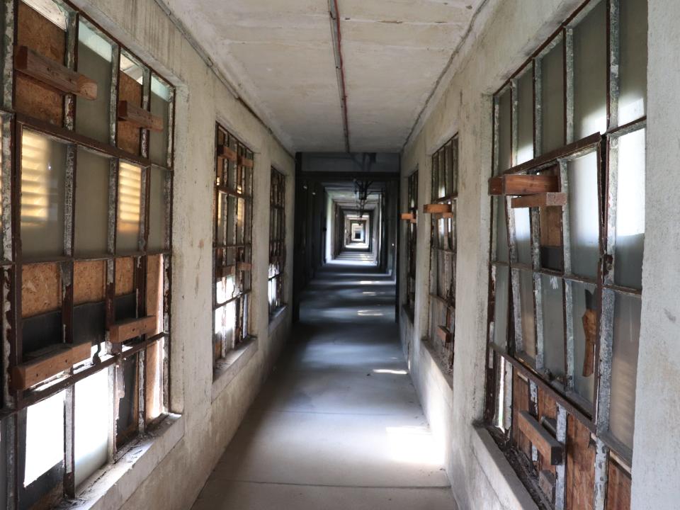 a long hallway of ellis island hospital with boarded up windows