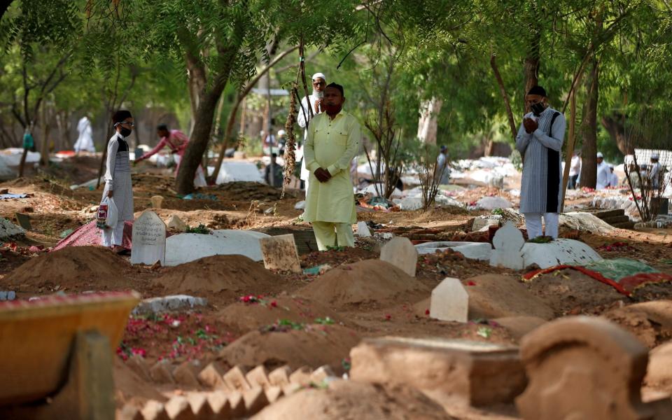 Muslims pray next to the graves of Covid-19 victims in Ahmedabad, India - Reuters