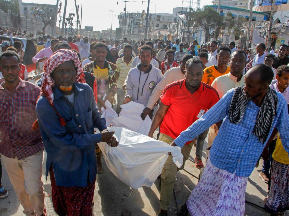 Relatives remove a body from the scene after a double car bomb attack at a busy junction in Mogadishu, Somalia