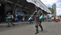 Sri Lankan government soldiers in protective clothes spray disinfectants at a railway station in Colombo, Sri Lanka, Wednesday, March 18, 2020. For most people, the new coronavirus causes only mild or moderate symptoms. For some, it can cause more severe illness, especially in older adults and people with existing health problems. (AP Photo/Eranga Jayawardena)