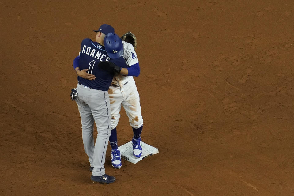 Los Angeles Dodgers' Mookie Betts gets a hug from Tampa Bay Rays shortstop Willy Adames after stealing second during the fifth inning in Game 1 of the baseball World Series Tuesday, Oct. 20, 2020, in Arlington, Texas. (AP Photo/David J. Phillip)