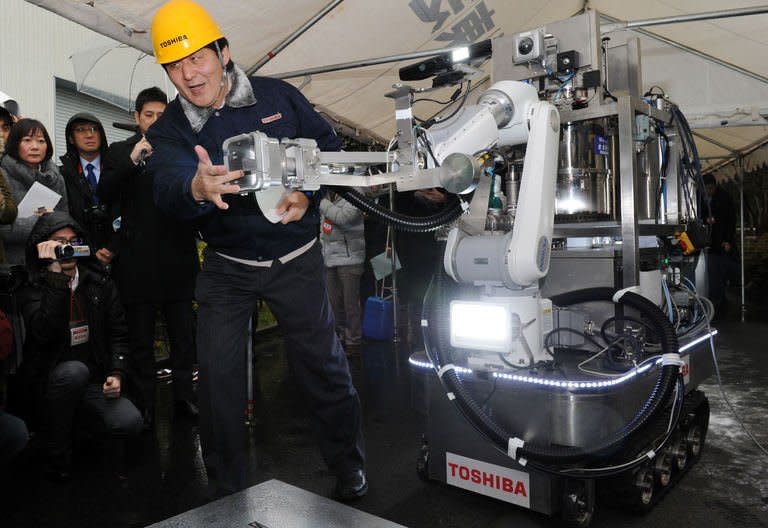 An engineer of Toshiba displays a decontamination robot, for work inside a nuclear plant, during a demonstration at Toshiba's technical center in Yokohama, suburban Tokyo on February 15, 2013. The crawler robot blasts dry ice particles against contaminated floors or walls and will be used for the decontamination in TEPCO's stricken Fukushima nuclear power plant