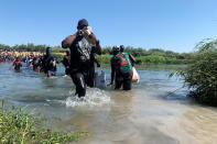 Migrants find an alternate place to cross between Mexico and the United States after access to a dam was closed, Sunday, Sept. 19, 2021, in Ciudad Acuña, Mexico. U.S. officials said that within the next few days, they plan to ramp up expulsion flights for some of the thousands of Haitian migrants who have gathered in the Texas city from across the border in Mexico. (AP Photo/Sarah Blake Morgan)