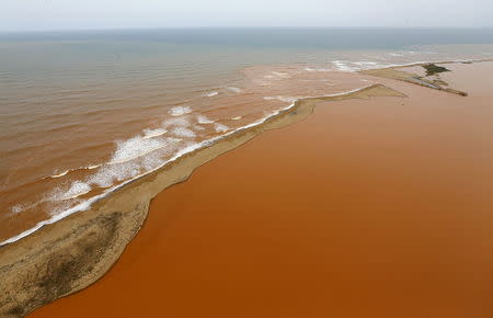 An aerial view of the Rio Doce (bottom) at an area where the river joins the sea (top) on the coast of Espirito Santo in Regencia Village, Brazil, November 23, 2015. The sheer volume of water disgorged by the dams and laden with mineral waste across nearly 500 km is staggering: 60 million cubic meters, the equivalent of 25,000 Olympic swimming pools or the volume carried by about 187 oil tankers. REUTERS/Ricardo Moraes