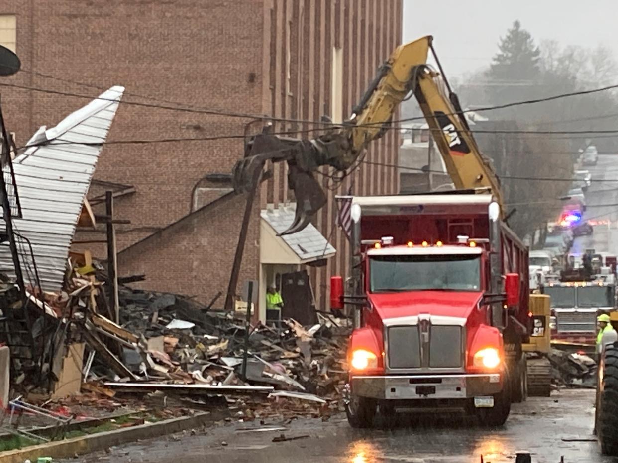 Construction vehicles clean up the debris from a Friday evening explosion that killed at least two people.