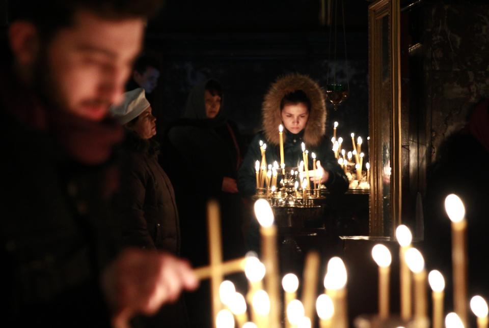 People light candles during a religious service at a church in Kiev
