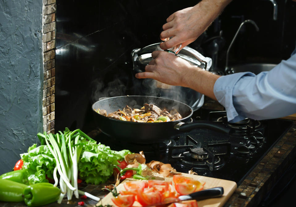 A home chef adds spices to a pan.